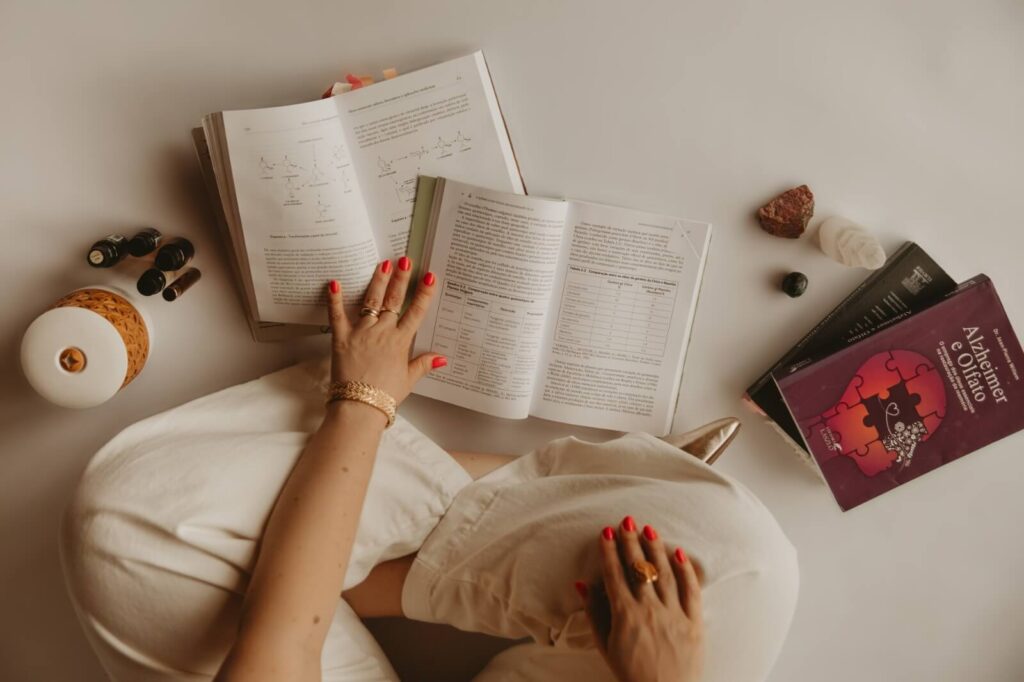 Mãos da Camila Castellan sobre livros de estudo de aromaterapia e neurociência
