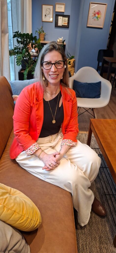 Dra. Camila Castellan, aromaterapeuta clínica, sentada no sofá e sorrindo