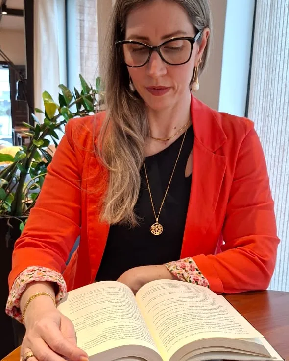 Dra. Camila Castellan estudando, com um livro aberto sobre a mesa